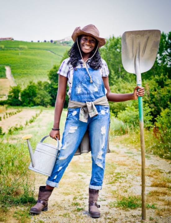 Loqi (a young female farmer) with a spade and a bucket in her hands